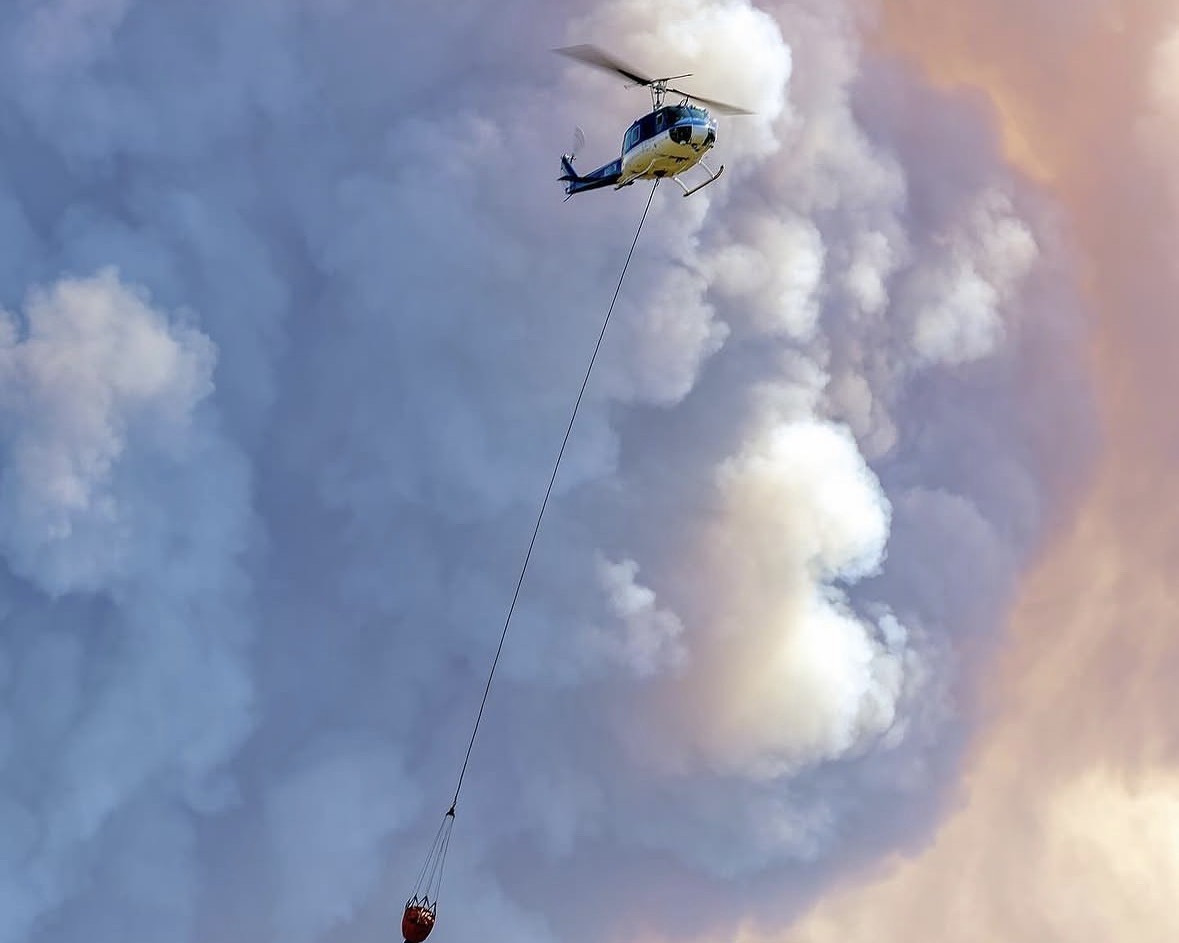Bell UH-1H on a bucket line in front of a smoke column