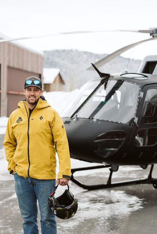 A Base Camp Aviation pilot on the ramp holding a flight helmet